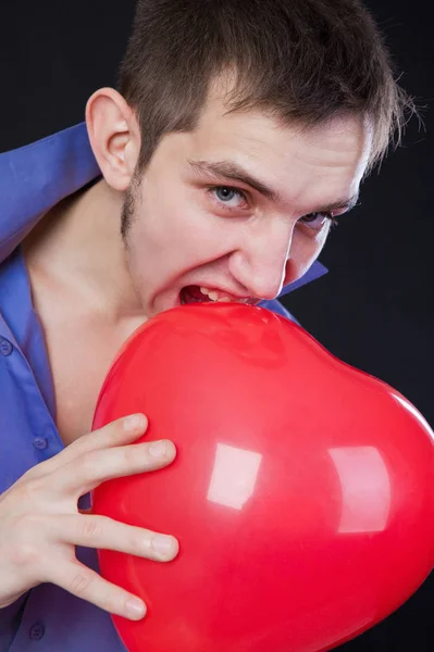 Young guy holding a red heart-shaped balloon — Stock Photo, Image