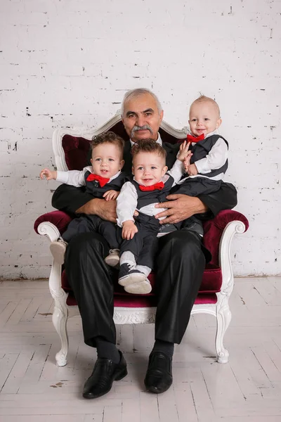 三つ子の孫の肖像画スタジオ撮影との祖父 — ストック写真
