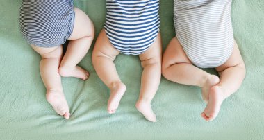 Newborn triplets lie on a stomach on a blanket clipart