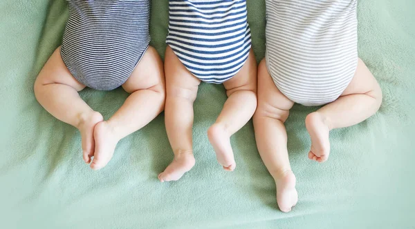 新生儿三胞胎躺在毛毯上的肚子上 — 图库照片