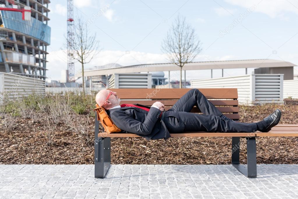 businessman lying down on bench