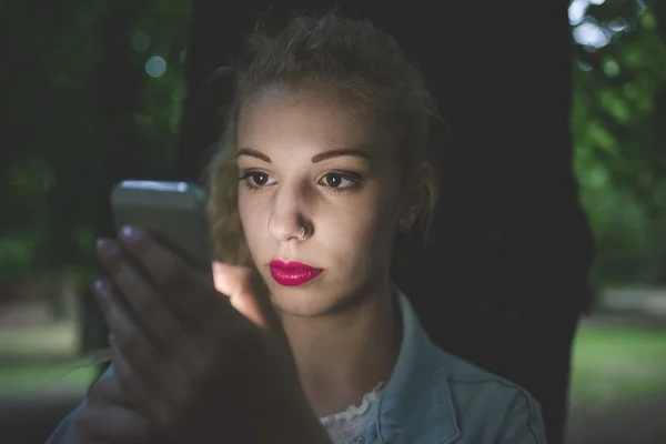 Woman with face illuminated by smartphone — Stockfoto