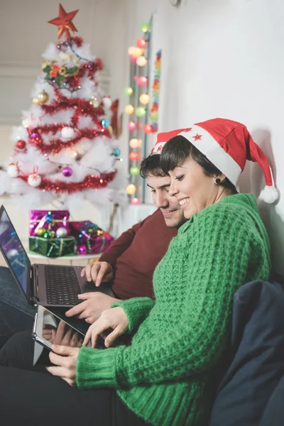 Par med santa claus hattar med hjälp av dator — Stockfoto