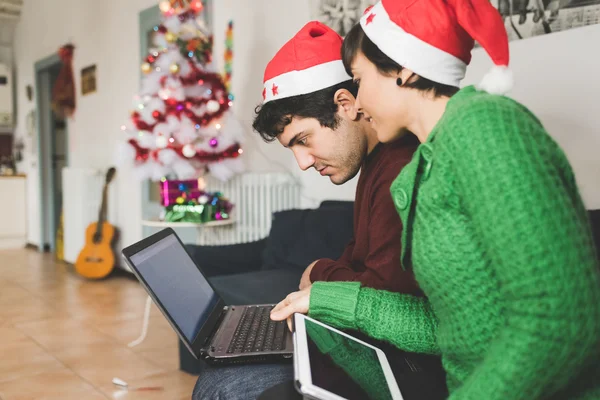 Couple with santa claus hat on sofa — Stock Photo, Image