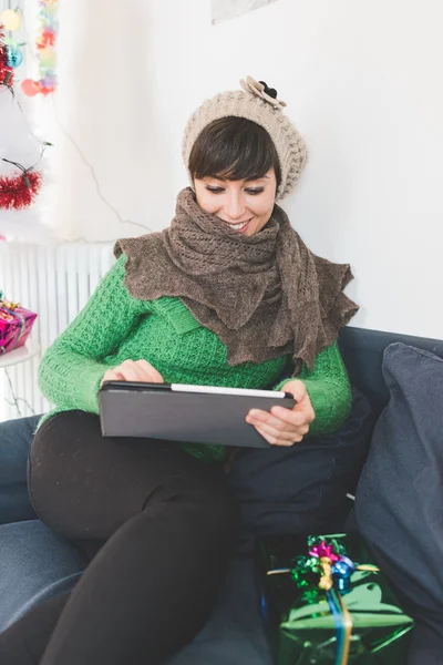 Kobieta siedzi na kanapie, trzymając tabletkę — Zdjęcie stockowe