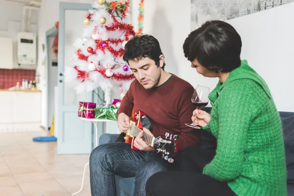 Couple sitting on sofa playing guitar — Stock fotografie