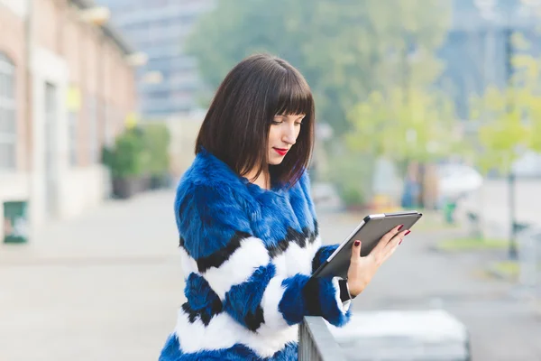 Femme appuyé contre le mur regardant tablette — Photo