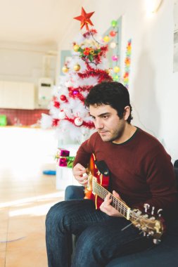 kanepenin üstüne oturan adam gitar çalmak