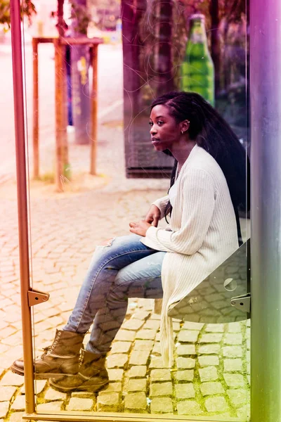 Mulher negra sentada na paragem de autocarro — Fotografia de Stock