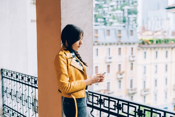 Vrouw leunend op balkon met smartphone — Stockfoto