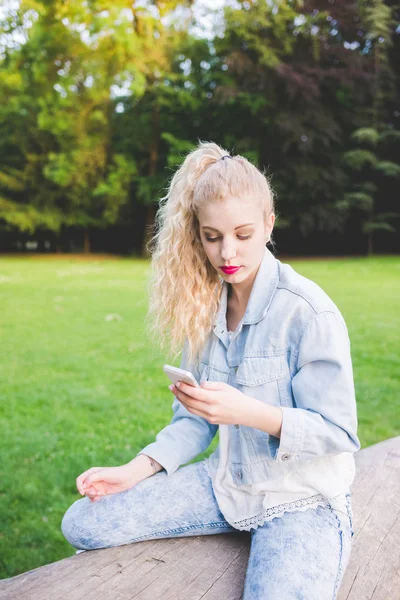 Kvinna utomhus på stammen med smartphone — Stockfoto