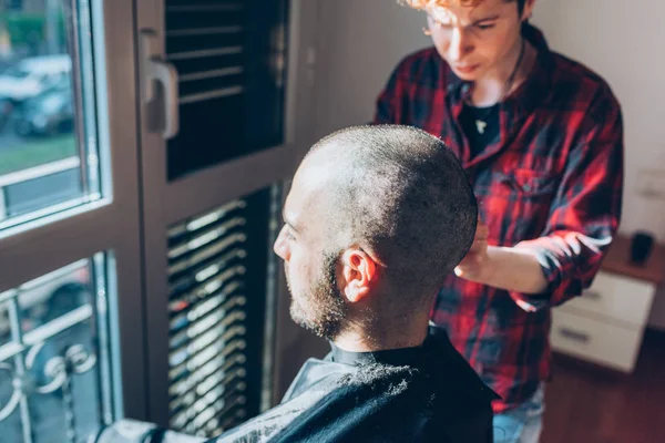 Woman barber cutting hair using razor
