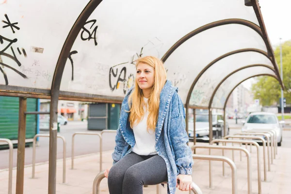 Blond kobieta siedzi w mieście — Zdjęcie stockowe