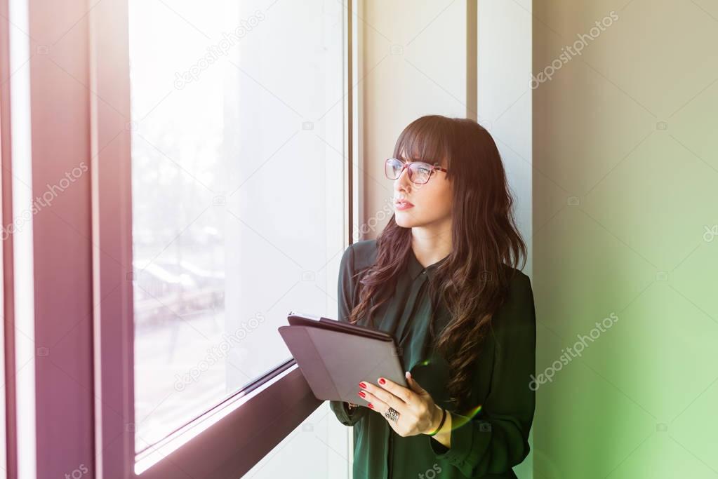 businesswoman near window holding tablet