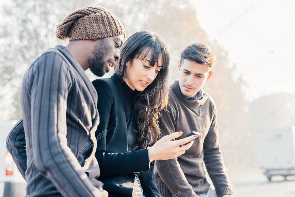multiethnic friends holding smartphone 