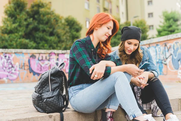 Mujeres sentadas en la escalera usando un teléfono inteligente — Foto de Stock