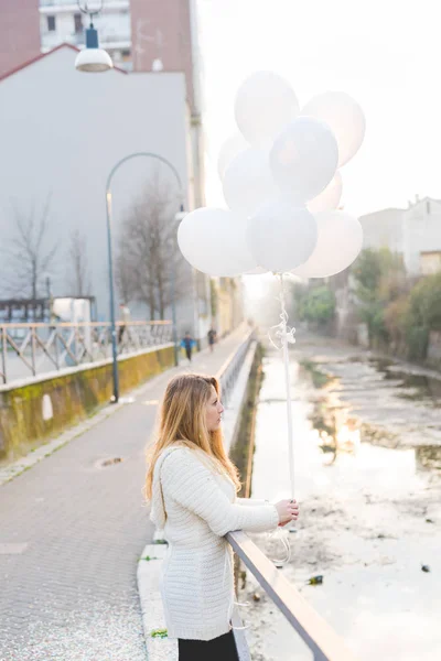 Femme en ville tenant des ballons blancs — Photo