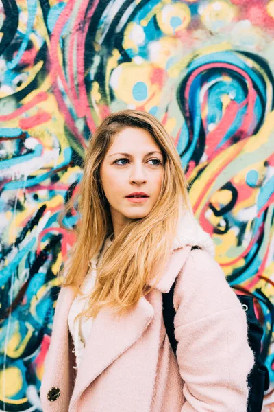 Kvinnan lutar sig på en färgstark vägg — Stockfoto