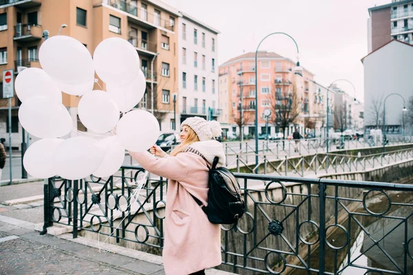 Vrouw in de stad houden van witte ballonnen — Stockfoto