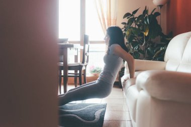 Genç, güzel, doğulu bir kadın evdeki oturma odasında yoga yapıyor. Rahatlatıcı, meditasyon, sessiz bir konsept.