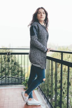 Genç doğulu güzel kadın balkonda dikiliyor, kameraya bakıyor - sakin, düşüncesiz, kaygısız konsept