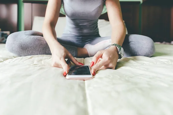 Woman using smartphone sitting bed — Stock Photo, Image