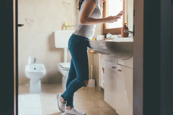 浴室里一个拿着智能手机刷牙的无法辨认的女人 希伯来语 交流理念 — 图库照片
