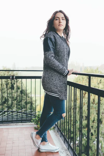 Genç doğulu güzel kadın balkonda dikiliyor, kameraya bakıyor - sakin, düşüncesiz, kaygısız konsept