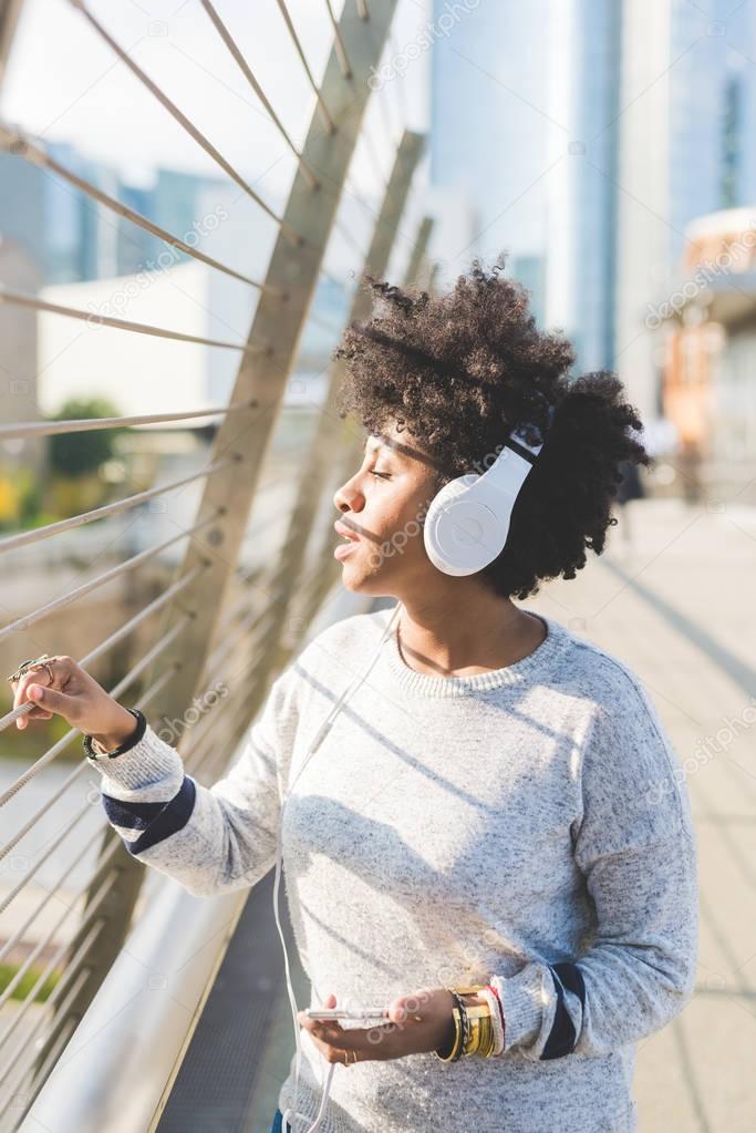 afro woman in city listening music 