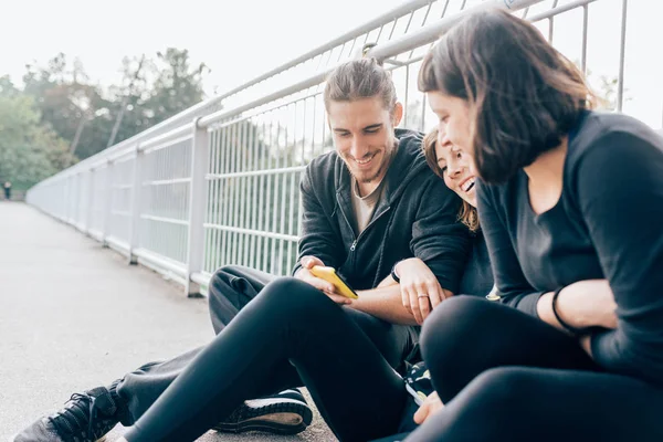 Kvinnor och mannen i staden ser på smartphone — Stockfoto