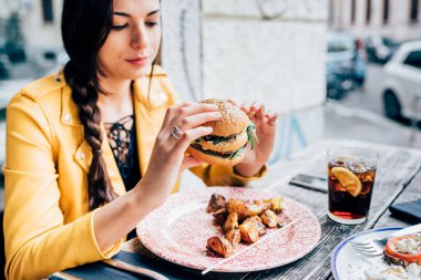 woman sitting eating hamburger