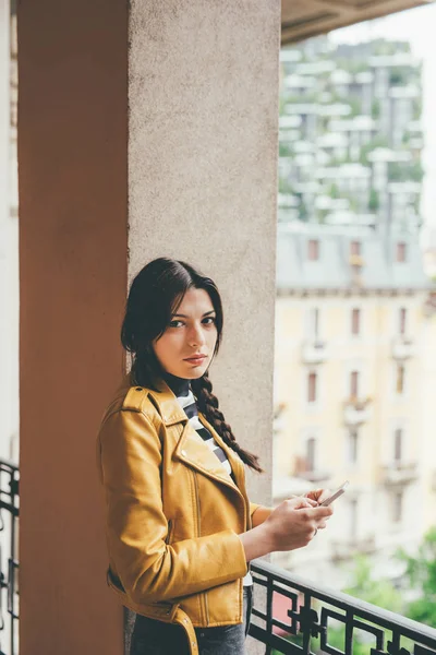 倚在阳台上使用智能手机的女人 — 图库照片