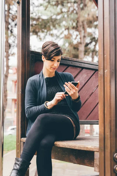 Vrouw in playgroung bezit smartphone — Stockfoto