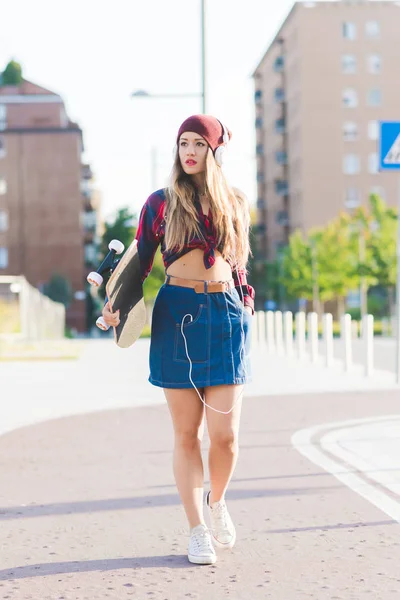 Mulher andando ao ar livre segurando skate — Fotografia de Stock