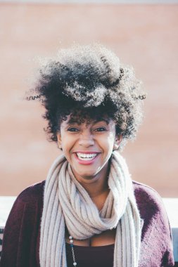 Kadın kameraya bakıp gülümsüyor.