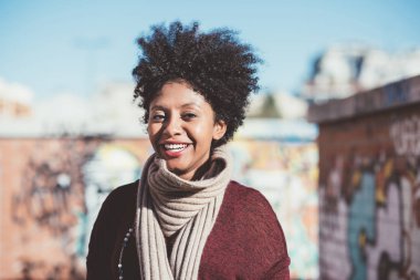 Kadın kameraya bakıp gülümsüyor.