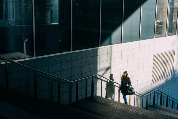 Frau geht mit Smartphone die Treppe hinauf — Stockfoto