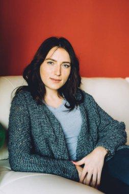 Genç, güzel bir kadın, bir kanepede oturmuş kameraya bakıyor. Huzurlu bir daire. Müşteri, sakin, tasasız bir konsept.