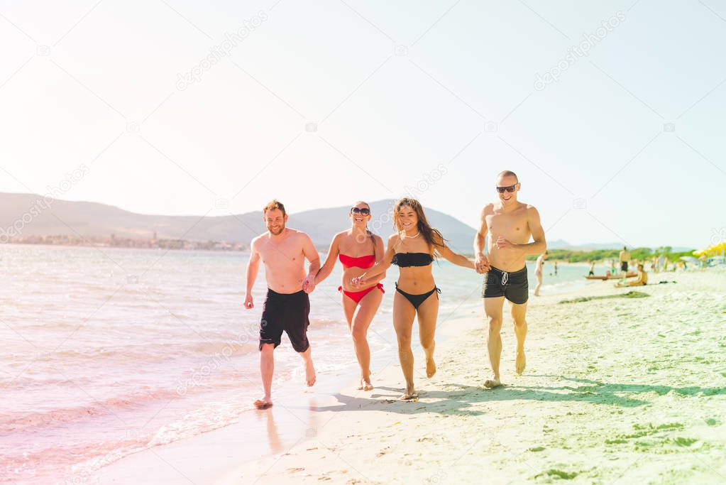 friends running holding hands on seashore