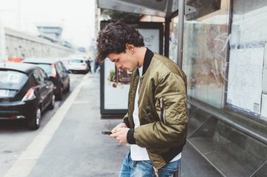 adam akıllı telefon kullanarak otobüs durağında