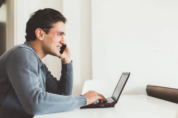 Uomo parlando smartphone utilizzando il computer — Foto Stock