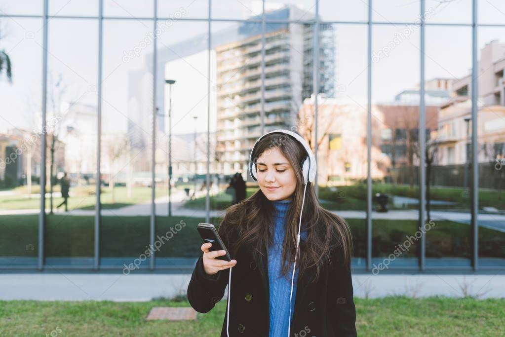 woman posing in city listening music 