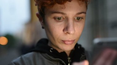 Akıllı telefon kullanan genç lezbiyen kadın portresi, ekran ışığı gece hayatı, intenret, iletişim konsepti tarafından aydınlatılmış yüz.