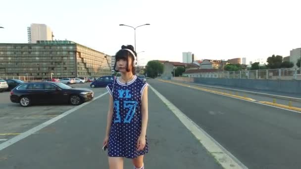 Headphons のスマート フォンで音楽を聴く都市で歩く若いアジア女性 — ストック動画