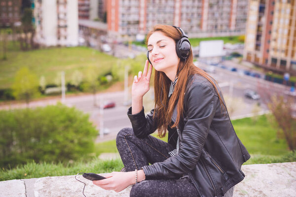 girl listening music in park in city 