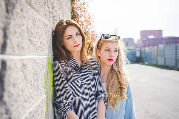 Meninas se divertindo posando em uma parede — Fotografia de Stock