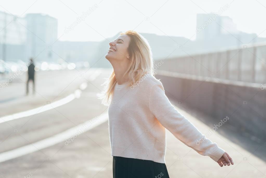 young woman outdoor back light arms raised laughing - freedom, victory, satisfaction concept