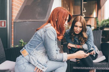 iki genç kadın eğleniyor - akıllı telefon kullanarak açık teknoloji, sosyal ağ, iletişim kavramı 