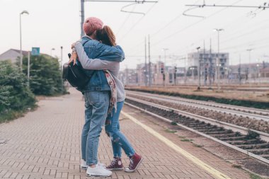 İki genç kadın dışarıda tren istasyonuna sarılıyor. Elveda, ayrılık, hüzün konsepti.