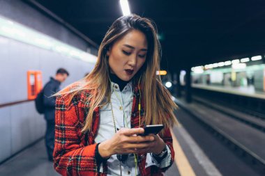 Akıllı telefon kullanan genç bir kadın. Teknoloji, işe gidiş gelişler, gezgin konsepti.